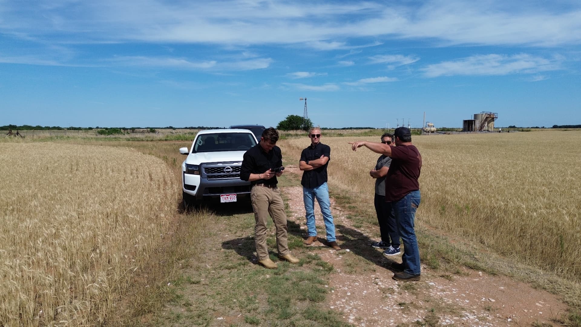Team reviewing a lease with an operator beside a truck in a wheat field